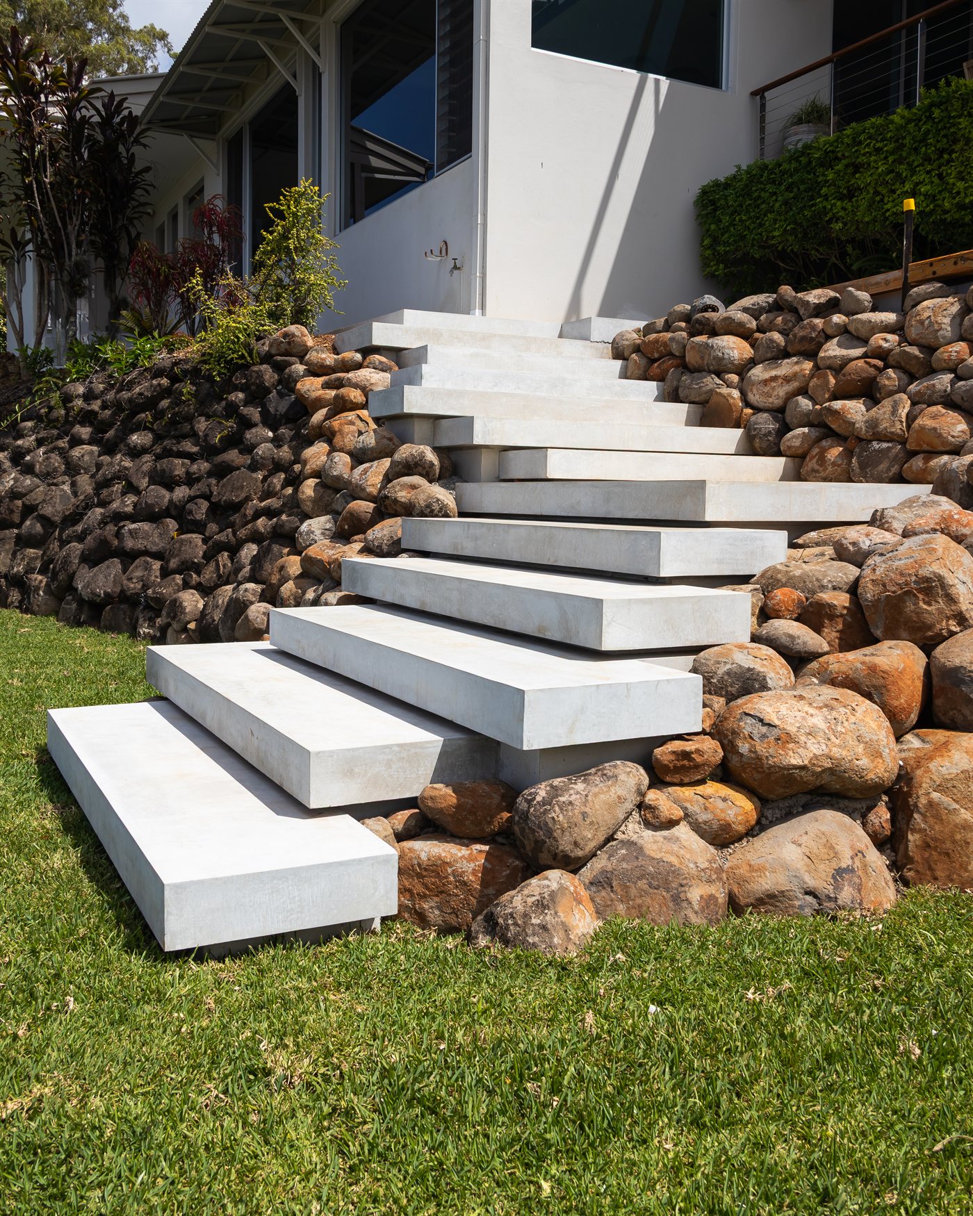Floating concrete steps set into a rock retaining wall and lawn