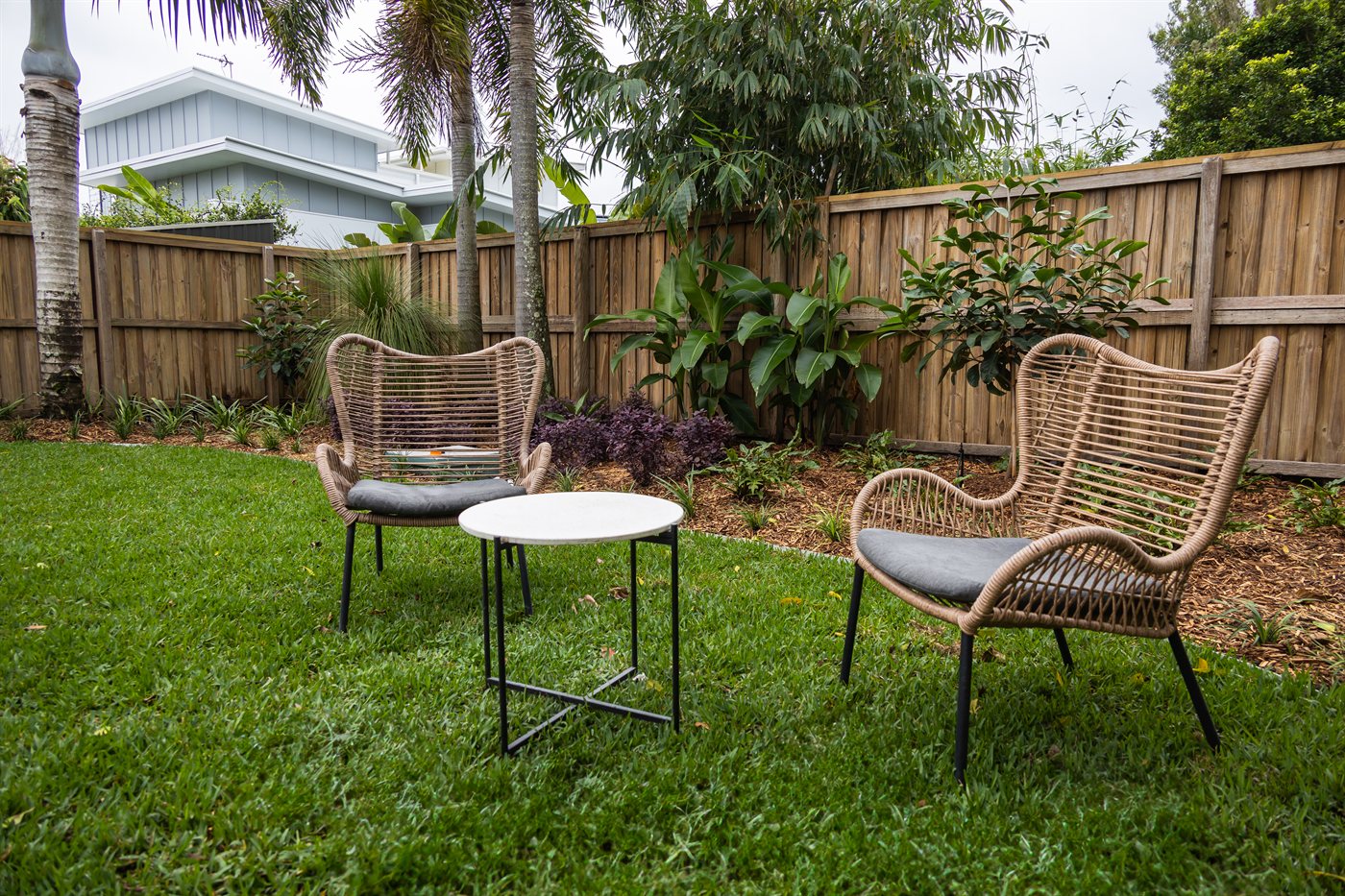 Landscaped backyard entertaining space with lawn, garden beds and outdoor seating