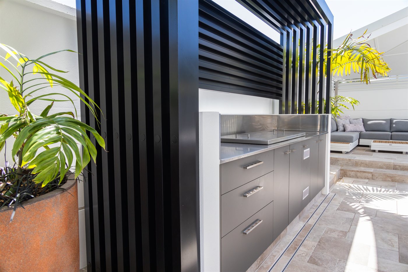 Outdoor kitchen with stainless steel benchtop and black batten screen