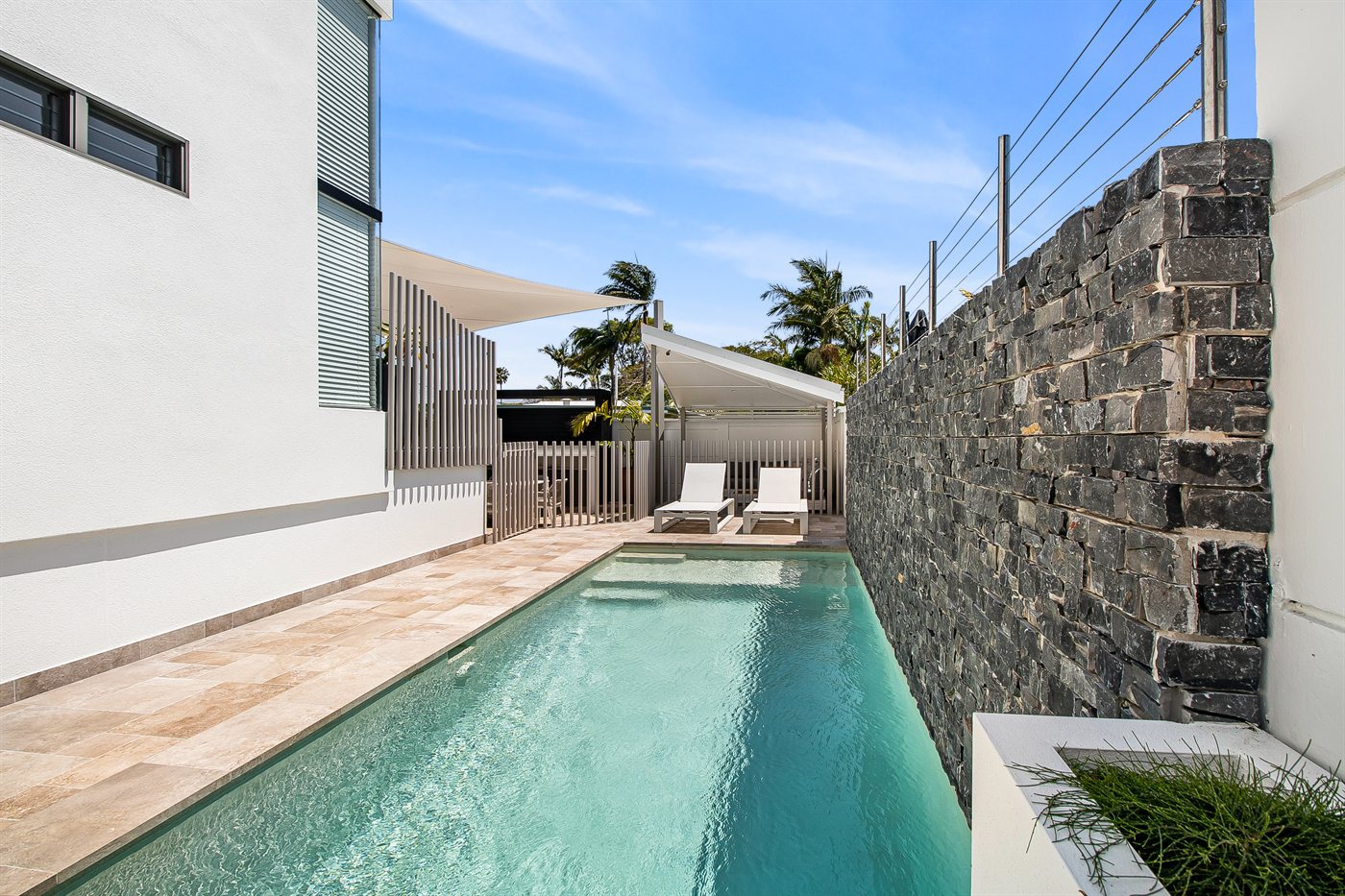 Lap pool set between a rendered wall and stone feature wall on a Sunshine Coast property